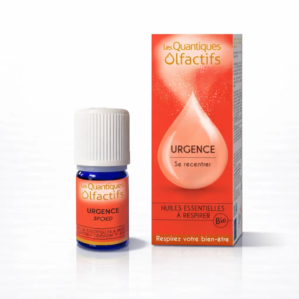 Un flacon de complexe d'huiles essentielles bio "Urgence" de la gamme Les Quantiques Olfactifs, accompagné de son étui rouge vif, présenté avec son reflet sur un fond blanc.