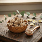 Morceaux de résine ou racine d'encens Mandragore, de couleur brun-beige terreux, dans un petit bol en bois avec cuillère, sur une planche de bois rustique.