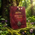 Livre rouge Harry Potter Recettes de Fêtes posé dans la mousse, illustré d'un Vif d'Or et du blason de Poudlard sous une lumière magique.