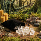 Sac en velours noir déversant un ensemble de Runes - Pierre cristal de roche transparentes sur une table en bois moussu, entouré de bougies en cire d'abeille.