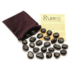 Set de runes en onyx noir gravées dorées, avec pochette en velours marron et fiche d’information sur les runes, sur fond blanc.