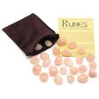 Set de runes en quartz rose gravées dorées, avec pochette en velours marron et fiche d’information sur les runes.