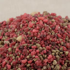 Gros plan sur un tas de grains d'encens de résine Sacré-Cœur de Jésus, dominé par des teintes de rose vif et de bordeaux, avec quelques touches de blanc/beige.