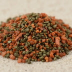 Gros plan sur un monticule de grains d'encens de résine Saint-Esprit, montrant un mélange de teintes orange-terre cuite et vert olive foncé.