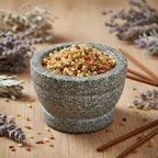 Grains d'encens de résine Saint Gabriel (jaune et multicolore) dans un mortier en granit, entouré de brins de lavande séchée et de bâtonnets d'encens.