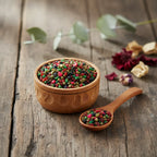 Grains d'encens de résine Saint Georges, très colorés (vert, rouge, noir), dans un petit bol en bois avec une cuillère, sur une planche de bois rustique.