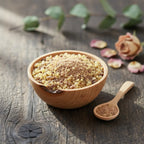 Grains d'encens de résine Saint Michel, mélange de résine ambrée claire et de poudre marron foncé, dans un bol en bois clair avec cuillère, sur une planche rustique.