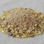 Gros plan sur un monticule de grains d'encens de résine Saint Michel, montrant des morceaux de résine jaune ambrée recouverts d'une poudre brun-beige, sur un fond en tissu clair.
