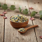 Coupelle en bois remplie de grains d’encens Saint Paul multicolores avec petite cuillère sur table en bois.