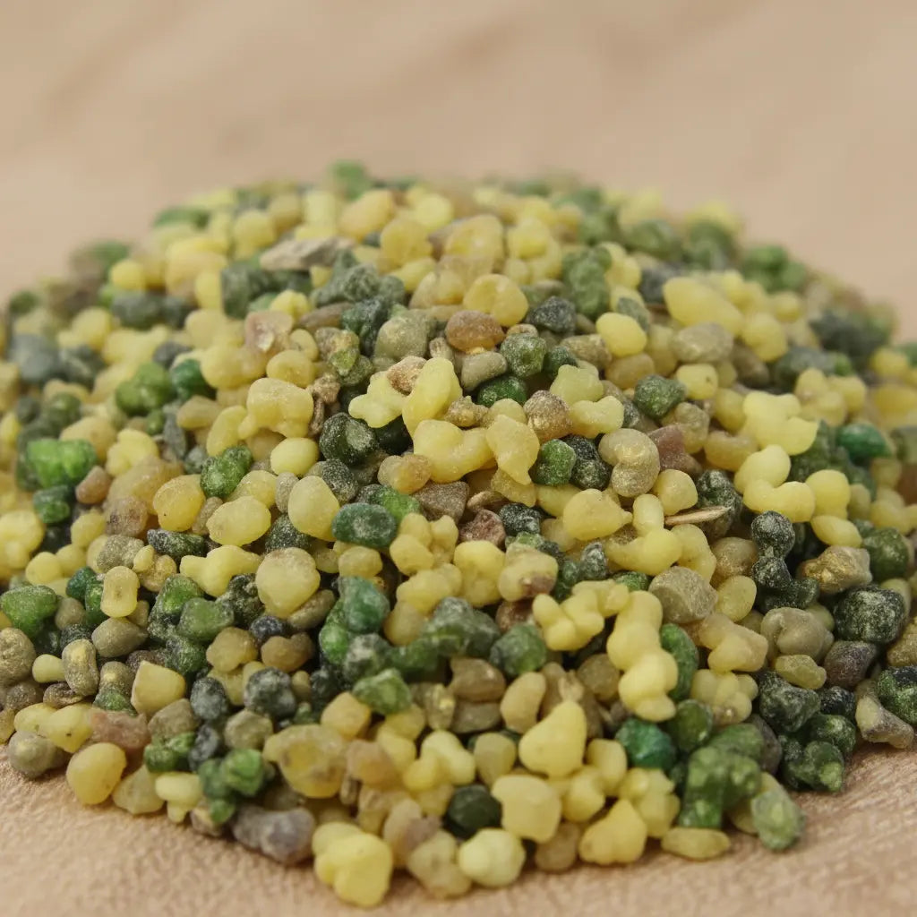Gros plan sur un tas de grains d'encens de résine Saint Raphaël, mélange de teintes vertes et jaunes pâles.