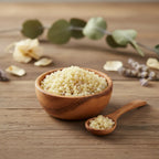 Grains de résine d'Encens Sandaraque, de couleur blanc ivoire et jaune pâle, dans un petit bol en bois d'olivier avec une cuillère, sur une planche de bois rustique.