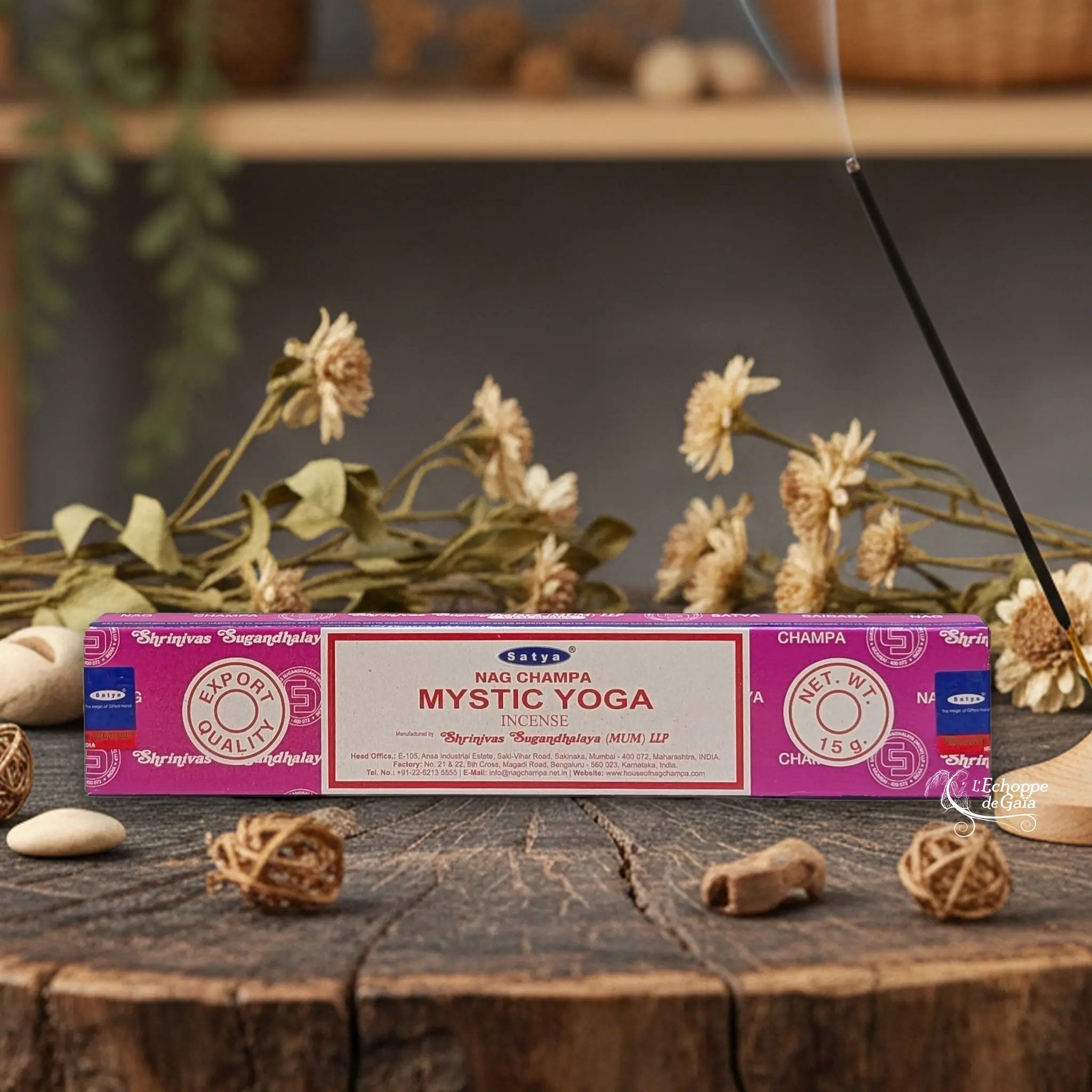 Boîte d'encens Satya Nag Champa "Mystic Yoga" posée sur une table en bois avec des fleurs séchées et un bâton d'encens fumant.