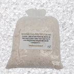 Sachet en organza blanc rempli de Sel de bain coco artisanal 200g sur un fond de cristaux blancs.