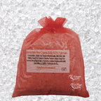 Sachet en organza rose rempli de Sel de bain framboise artisanal 200g sur un fond de cristaux blancs.
