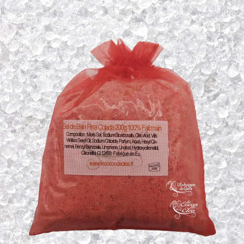 Sachet en organza rose rempli de Sel de bain framboise artisanal 200g sur un fond de cristaux blancs.