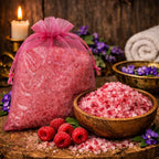 Cristaux de Sels de Bain Framboise rose vif dans un bol en bois avec framboises fraîches et sachet en organza rose.