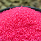 Gros plan sur des cristaux de sel infusé Accueil Chaleureux, texture cristalline rose vif.