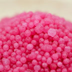 Gros plan sur les grains ronds rose vif intense du sel infusé Dragon Blood