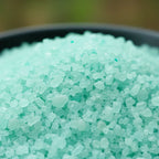 Gros plan sur les cristaux de sel turquoise vif et granuleux du sel infusé Jardin Secret.