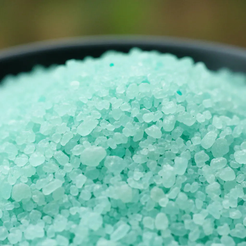Gros plan sur les cristaux de sel turquoise vif et granuleux du sel infusé Jardin Secret.