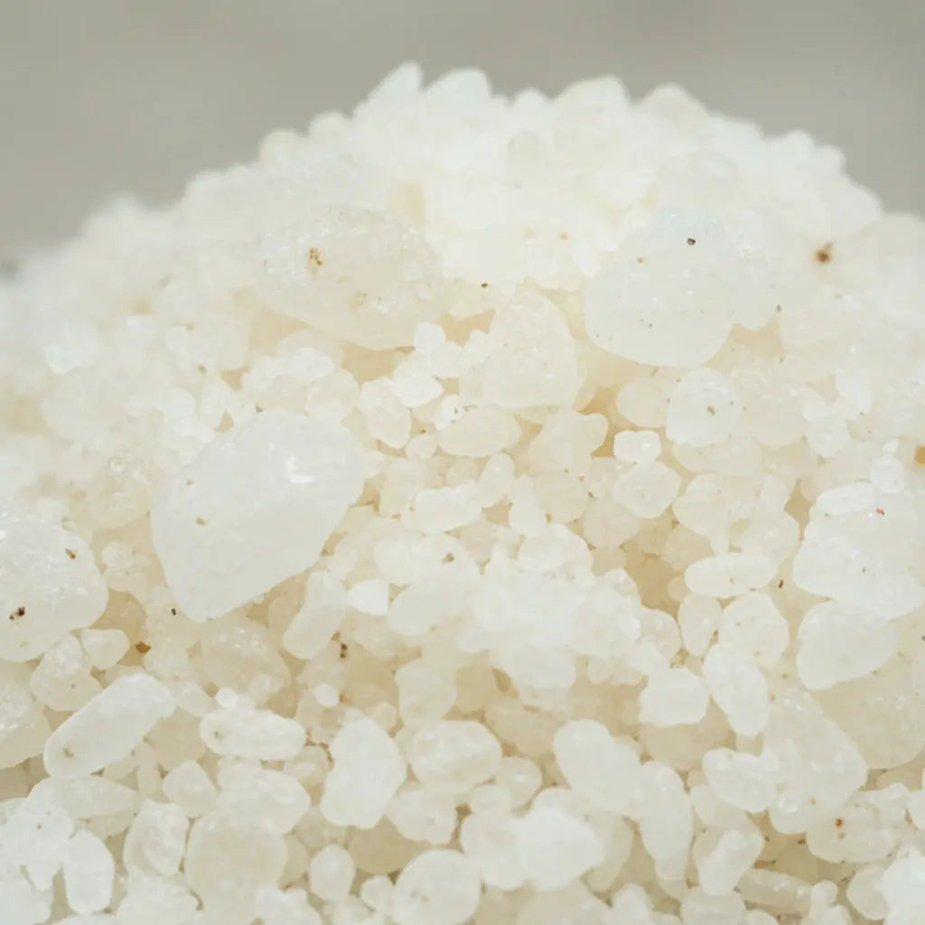 Gros plan sur les cristaux blancs irréguliers et bruts du sel infusé Oliban