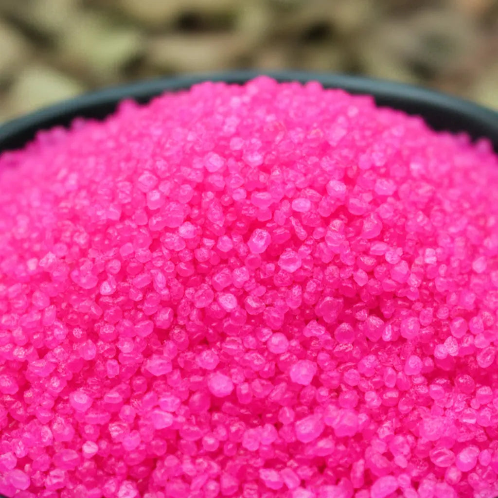 Gros plan sur des cristaux de sel infusé Passion Boudoir, texture cristalline rose vif.