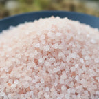 Gros plan sur des cristaux de sel infusé à la Vanille et au Musc, texture cristalline rose pâle.