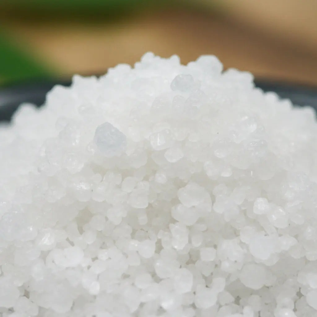 Gros plan sur des cristaux de sel infusé à la Lavande Blanche, texture cristalline blanche.