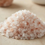 Gros plan sur un monticule de grains de Sel Rose de l'Himalaya, montrant des cristaux blancs et roses pâles de taille irrégulière.