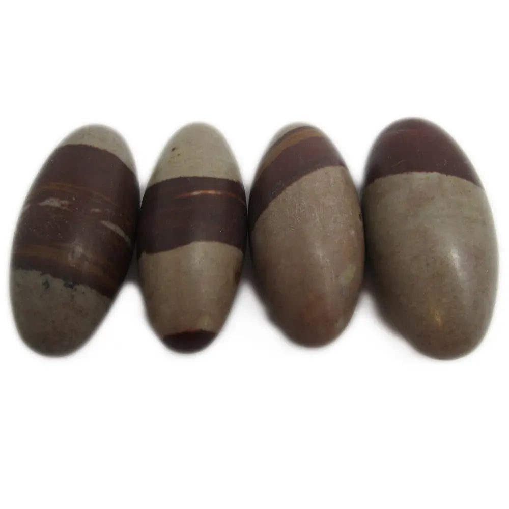 Quatre pierres de shiva lingam polies de forme ovoïde, présentant des zones beiges et des bandes brun-rougeâtre caractéristiques, alignées sur un fond blanc.