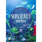 Couverture du livre Sorcières vertes - T3 : Le Manuel d'Ann Moura, présentant le titre dans un macaron bleu-violet sur fond de plantes verdoyantes et de petites fleurs bleues éclairées d'une lumière mystique, avec une fiole de liquide rouge visible sur le côté droit.