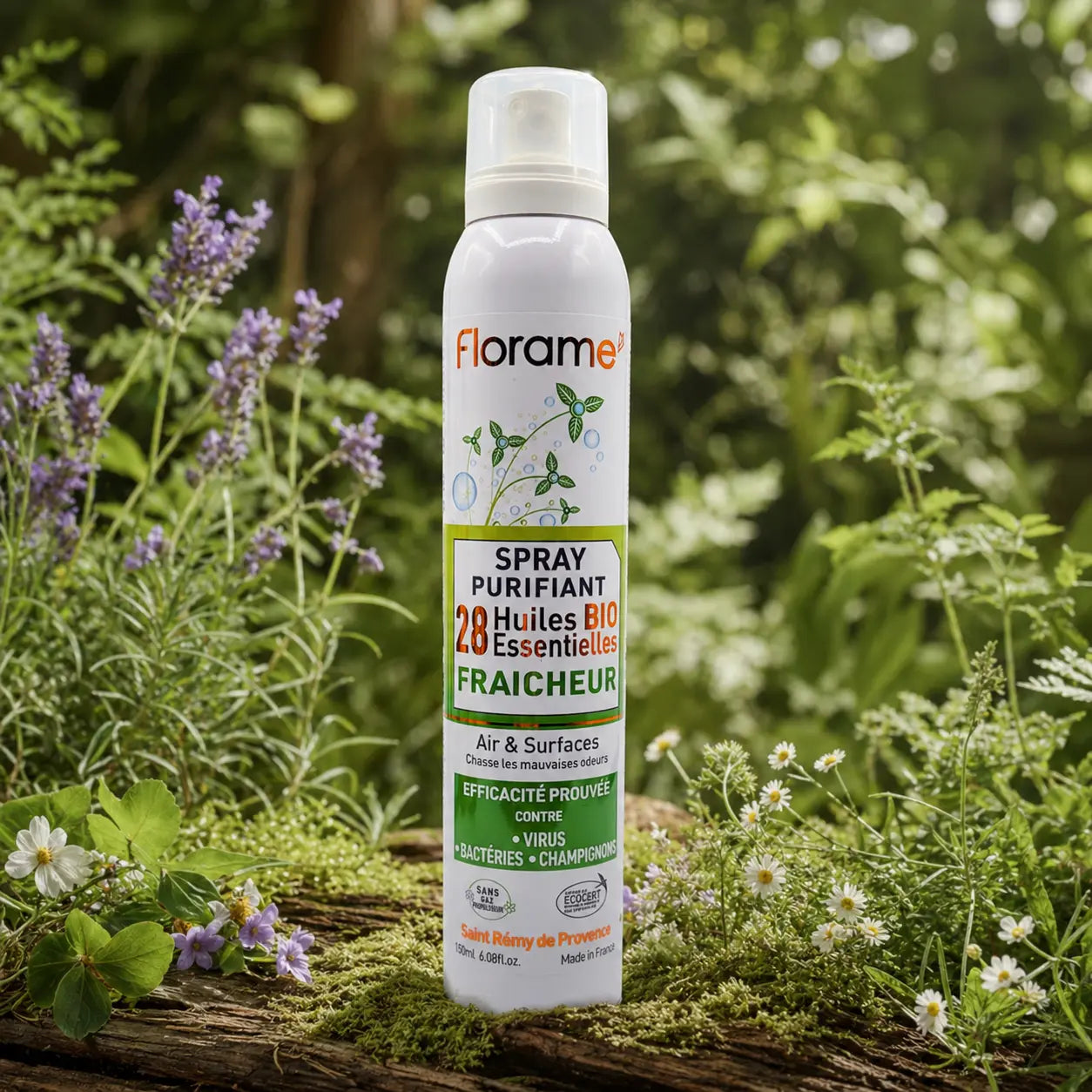 Spray purifiant bio Florame Fraîcheur au milieu d'une nature verdoyante, entouré de brins de lavande et de petites fleurs blanches sauvages.