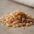 Gros plan sur des grains d’encens Saint Ange Gardien ambrés et dorés sur fond en bois.
