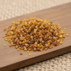 Gros plan sur des grains d’encens Sainte Thérèse dorés et ambrés sur planche en bois.
