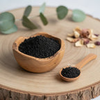 Encens de résine Storax (Styrax) en poudre noire et granuleuse, dans un petit bol en bois d'olivier avec une cuillère, sur une tranche de tronc d'arbre rustique.