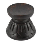 Support pour boule de cristal en bois sombre (noir/brun), forme de petit socle “lotus” : une base évasée sculptée de pétales arrondis tout autour, surmontée d’un col court et d’une coupelle circulaire plate en haut pour poser la boule. Finition mate, avec quelques nuances/brunissements visibles dans le bois. Photo détourée sur fond blanc.