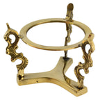 Support pour boule de cristal en laiton doré, composé d’un socle courbé et d’un anneau circulaire horizontal pour maintenir la boule. L’anneau est relié au socle par trois montants : deux pièces latérales décoratives en volutes (style arabesques) et un montant central plus droit avec une petite languette/ergot en haut. Photo détourée sur fond blanc.