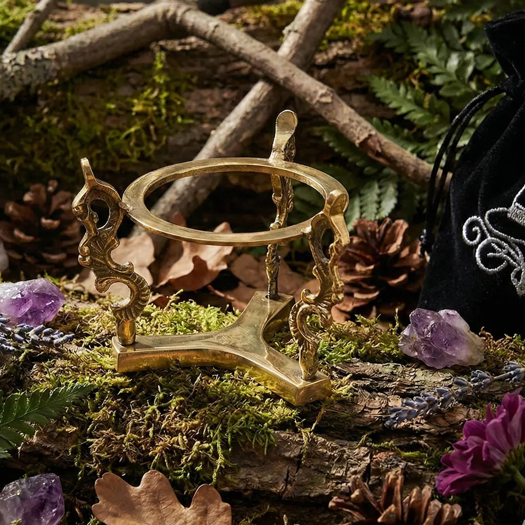 Support en laiton pour Boule de Cristal doré avec ornements sculptés posé sur un autel naturel.