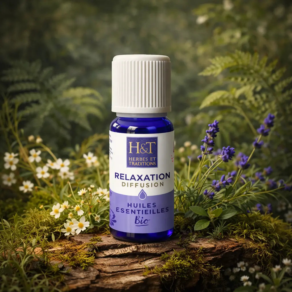 Flacon bleu d'huiles essentielles à diffuser Relaxation Herbes et Traditions posé sur une écorce moussue avec des fleurs de lavande et des petites fleurs blanches.