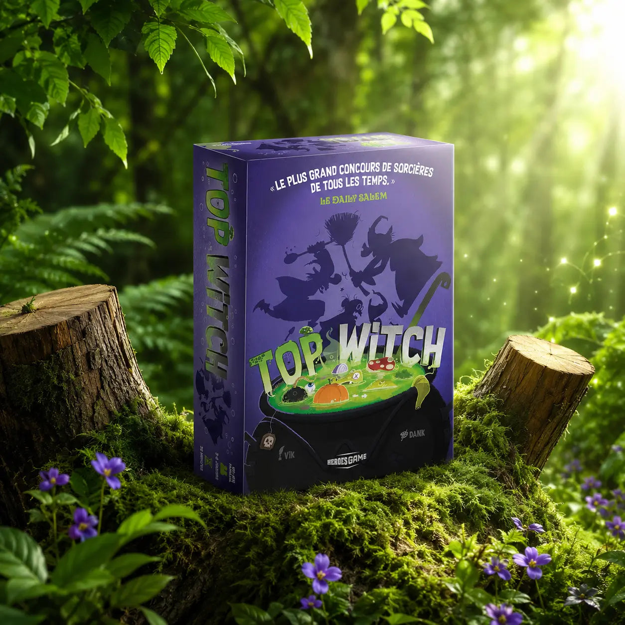 Boîte du jeu Top Witch de Vik posée sur un talus de mousse verte entre deux souches d'arbres dans une forêt lumineuse, avec de petites fleurs violettes.