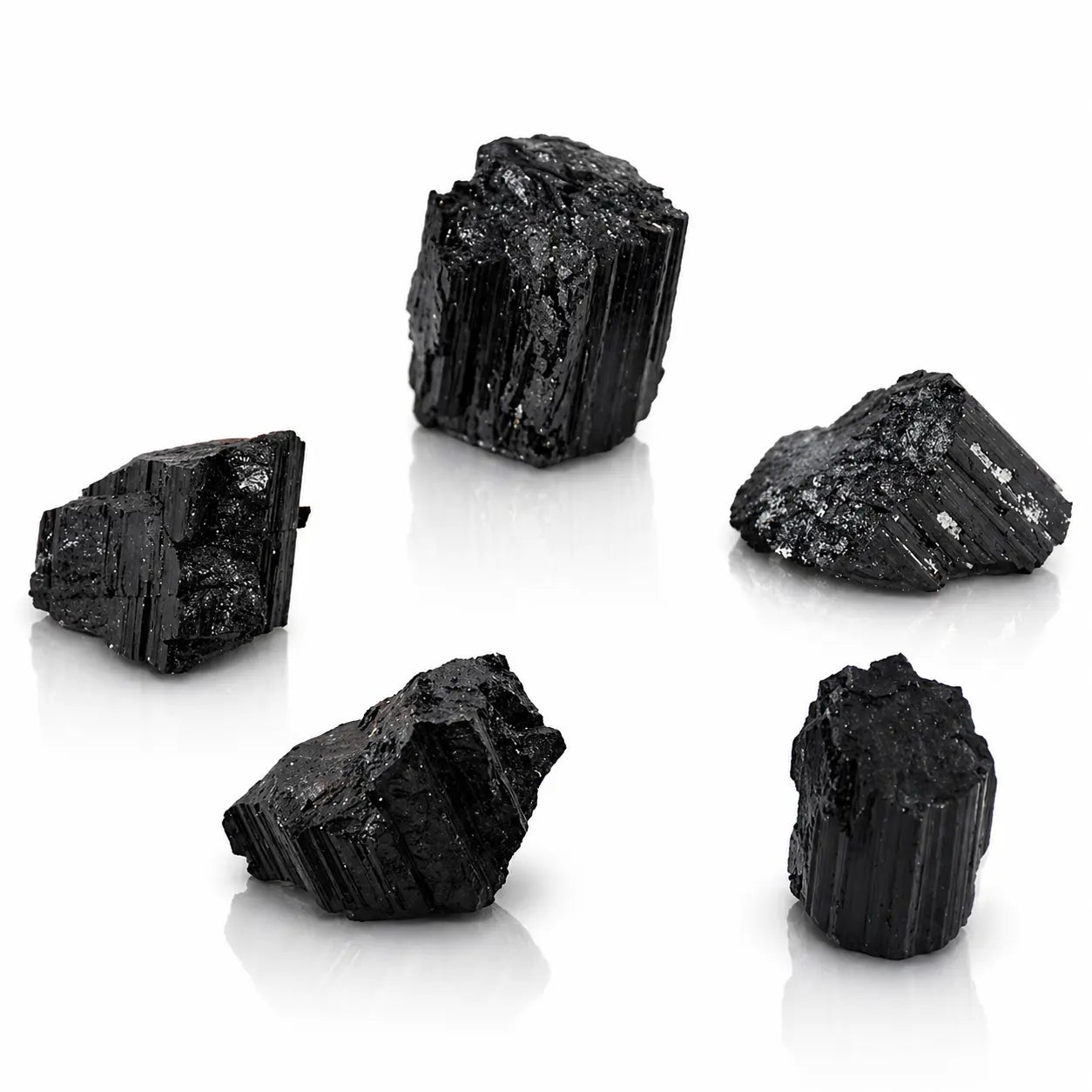 Groupe de cinq pierres de tourmaline noire brute montrant des structures fibreuses et striées sur fond blanc.