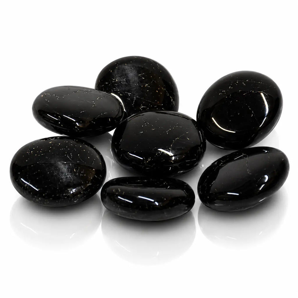 Ensemble de galets polis en tourmaline noire brillante avec reflets sur fond blanc.