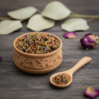 Coupelle en bois sculpté remplie de grains d’encens Vatican multicolores avec petite cuillère sur table en bois sombre.