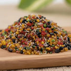 Gros plan sur des grains d’encens Vatican multicolores mélangés à des éclats d’herbes sur planche en bois.