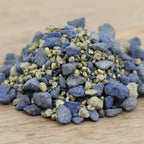 Gros plan sur un monticule de grains d'encens de résine Vierge Marie, montrant de gros morceaux bleu intense mélangés à des grains gris-beige et des touches dorées scintillantes.