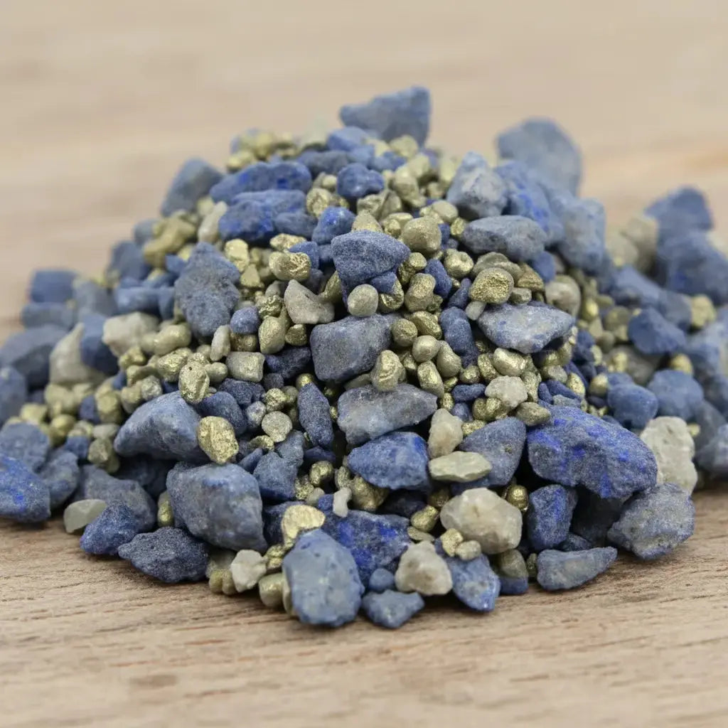 Gros plan sur un monticule de grains d'encens de résine Vierge Marie, montrant de gros morceaux bleu intense mélangés à des grains gris-beige et des touches dorées scintillantes.