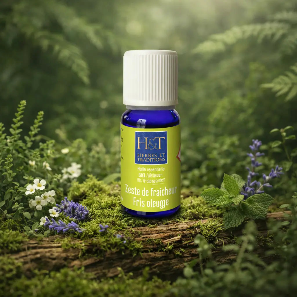 Flacon bleu et étui vert pomme Herbes et Traditions Zeste de Fraîcheur posé sur une branche moussue parmi des fleurs blanches et des brins de menthe.